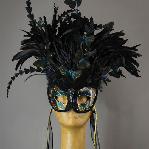 Beautiful Masquerade Mask, in iridescent shades over black. Crested with black coque feathers. Iridescent black feather butterflies flutter on the crest. Embellished with Swarovski crystals, and polished gemstones.  Hand made in the USA using traditional Venetian paper-mache technique. Lined with hypoallergenic stretch velvet for comfort. Detail.