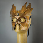 The Copper Warrior Bauta Masquerade mask is Inspired by medieval armor of the Renaissance. With it's masculine lines, this mask is particularly popular for men and is a lightweight and comfortable mask that is perfect for Halloween and Masquerade events. Mask is treated in shades of gold and copper with Dragon Wing panel armor, metal findings and assorted polished gems.  Handmade in the USA using traditional Venetian paper-mache techniques. Lined with hypoallergenic stretch velvet for comfort. Side view.