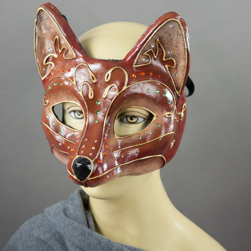 Fancy Red Fox Mask detail. A lightweight comfortable mask inspired by the sly red fox, decorated with an elegant gold scroll motif and embellished with Swarovski Crystals and assorted gems.  Hand Made in the USA using traditional Venetian paper-mache techniques and lined with soft stretch velvet for comfort.