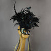 Beautiful Masquerade Mask, in iridescent shades over black. Crested with black coque feathers. Iridescent black feather butterflies flutter on the crest. Embellished with Swarovski crystals, and polished gemstones.  Hand made in the USA using traditional Venetian paper-mache technique. Lined with hypoallergenic stretch velvet for comfort. Side view.