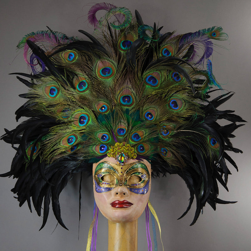 Stunning Full Face Mask with a luxe crest of black coque and assorted peacock tail feathers and plumage. Embellished with Swarovski crystals, and assorted polished gem stones. Sure to turn heads at any costume, masquerade or Halloween party!  Hand-made in the USA using traditional Venetian paper-mache technique. Lined with hypoallergenic stretch velvet for comfort.