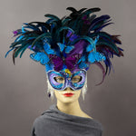 Beautiful Masquerade Mask, in shades of purple and blue. Crested with black, purple and blue hand dyed coque feathers and assorted plumage. Purple and blue feather Monarch butterflies flutter on the crest. Embellished with Swarovski crystals, seashells, freshwater pearls and polished stones with a small tree frog perched on top.  Hand made in the USA using traditional Venetian paper-mache technique. Lined with hypoallergenic stretch velvet for comfort.