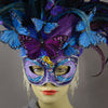 Beautiful Masquerade Mask, in shades of purple and blue. Crested with black, purple and blue hand dyed coque feathers and assorted plumage. Purple and blue feather Monarch butterflies flutter on the crest. Embellished with Swarovski crystals, seashells, freshwater pearls and polished stones with a small tree frog perched on top.  Hand made in the USA using traditional Venetian paper-mache technique. Lined with hypoallergenic stretch velvet for comfort. Detail.