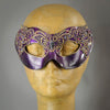 Metallic purple and black mask with butterfly motif lace accented in gold. Embellished with Swarovski crystals and polished gems.