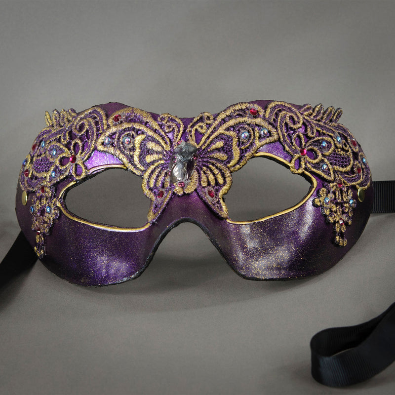 Metallic purple and black mask with butterfly motif lace accented in gold. Embellished with Swarovski crystals and polished gems. Detail.