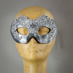 Simple, elegant eye mask in Metallic Silver and Black. Embellished with lacquered lace, glass gems, Swarovski crystals and polished stones.  Hand made in the USA using traditional Venetian paper-mache techniques. Lined in stretch velvet for comfort.