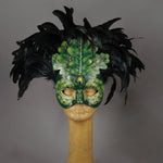 An apparition from the wooded forest, this beautiful Masquerade Mask, is one of our versions of the green man. With a backdrop crest of black coque feathers, the green handmade oak leaves stand proud. To add some sparkle, we embellished this mask with a complimentary palette of Swarovski crystals, dichroic glass and polished stones.  Hand made in the USA using traditional Venetian paper-mache technique. Lined with hypoallergenic stretch velvet for comfort.