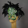 An apparition from the wooded forest, this beautiful Masquerade Mask, is one of our versions of the green man. With a backdrop crest of black coque feathers, the green handmade oak leaves stand proud. To add some sparkle, we embellished this mask with a complimentary palette of Swarovski crystals, dichroic glass and polished stones.  Hand made in the USA using traditional Venetian paper-mache technique. Lined with hypoallergenic stretch velvet for comfort. Side view.