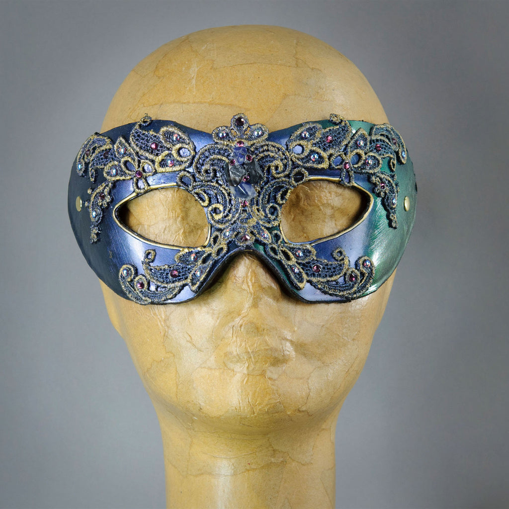 Simple, elegant eye mask in Iridescent Green, Blue and Black. Embellished with lacquered lace, glass gems, Swarovski crystals and polished stones.  Hand made in the USA using traditional Venetian paper-mache techniques. Lined in stretch velvet for comfort.